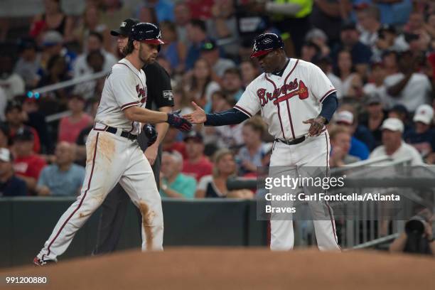 Charlie Culberson high-fives first base coach Eric Young of the Atlanta Braves against the Cincinnati Reds at SunTrust Park on June 26 in Atlanta,...