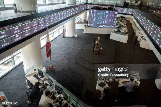 Traders work beneath a monitor and an electronic ticker at the trading floor of the Philippine Stock Exchange in Bonifacio Global City , Metro...