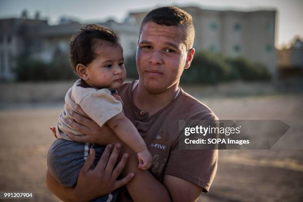 Syrian man holds his baby in a street in Mafraq. There are about 1.4 million Syrian refugees in Jordan and only 20 percent are living in the refugee...