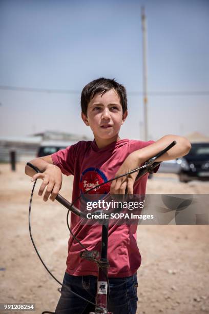 Young Syrian boy stands with his bike in Zaatari refugee camp. There are about 1.4 million Syrian refugees in Jordan and only 20 percent are living...