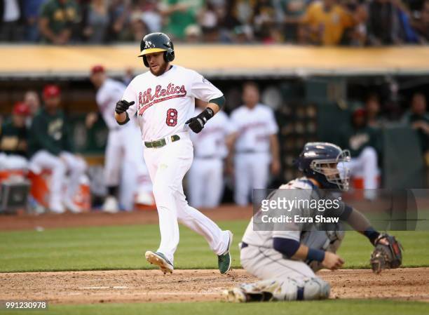 Jed Lowrie of the Oakland Athletics runs past Austin Hedges of the San Diego Padres to score in the sixth inning at Oakland Alameda Coliseum on July...