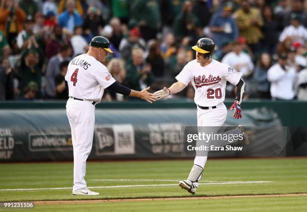 Mark Canha of the Oakland Athletics is congratulated by third base coach Matt Williams as he rounds the bases after hitting a home run in the sixth...