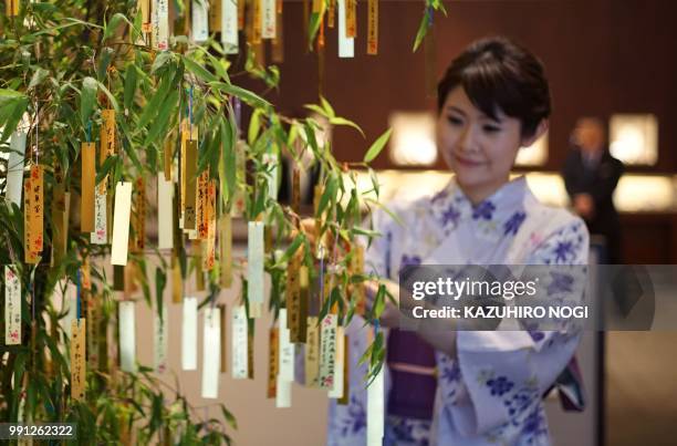 An employee of jewelry store Ginza Tanaka hangs a gold leaf strip wishing card onto a bamboo decoration during the annual celebration of July 7...