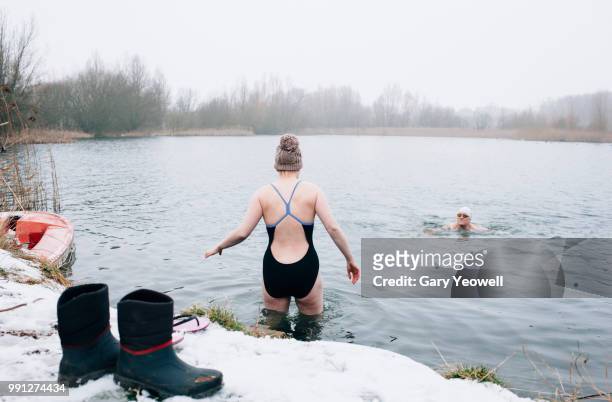 male and female open water swimmers in winter - gefrorener see stock-fotos und bilder
