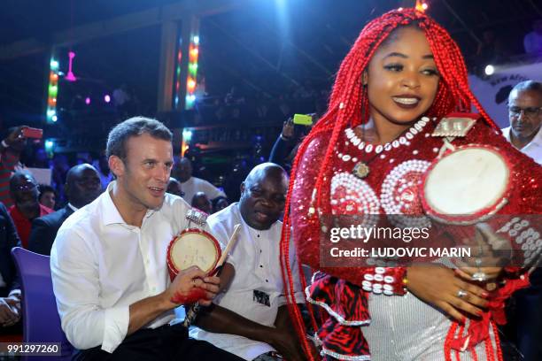 French President Emmanuel Macron plays a talking drum as he joins in at a performance at the Shrine Afrika in Lagos on July 3, 2018. - French...