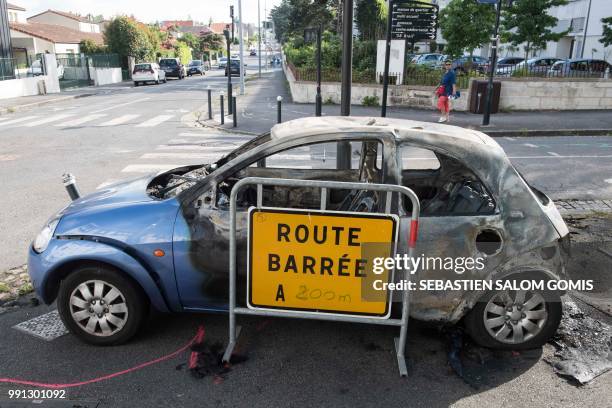 Picture taken on July 4, 2018 in the Breil neighborhood of Nantes shows a burned car following clashes between groups of young people and police in...