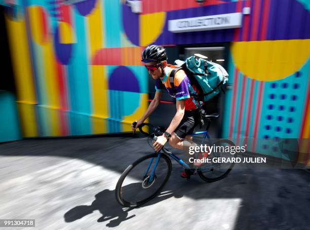 Biker working for the Food delivery service Deliveroo cycles off to deliver an order on July 3, 2018 in Saint-Ouen, outside Paris. - Deliveroo, which...