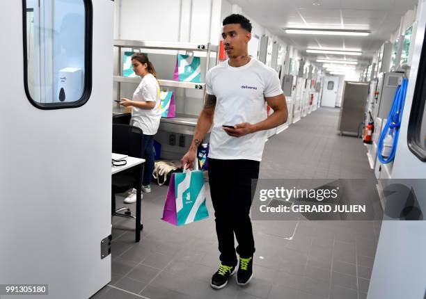 Deliveroo worker carries a delivery at one of the first Deliveroo Editions in France kitchens on July 3, 2018 in Saint-Ouen, outside Paris. -...