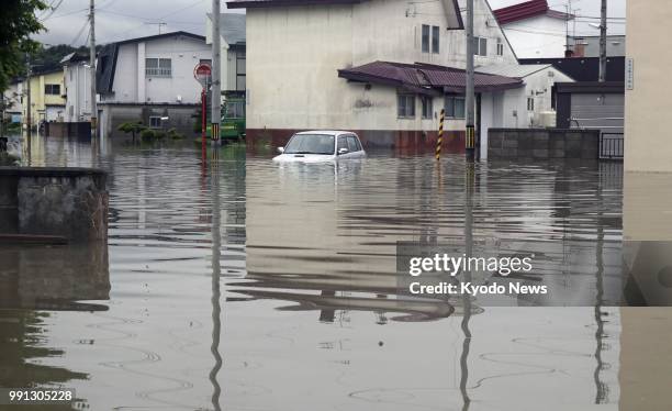 Car is seen on a flooded road in Asahikawa in Japan's northernmost main island of Hokkaido on July 3 following heavy rain. Some 130 people were...