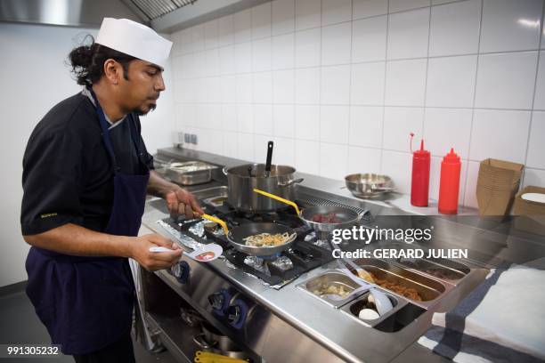 Cook prepares a meal in one of the kitchens of the first kitchen Deliveroo Editions in France on July 3, 2018 in Saint-Ouen, outside Paris. -...