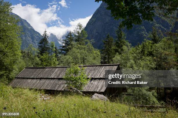 With the highest peaks in Slovenia in the distance is a traditional Slovenian mountain hut in the Slovenian Julian Alps, on 22nd June 2018, in...