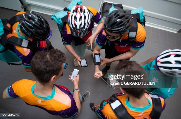 Bikers working for the food delivery service Deliveroo wait for their instructions at one of the first Deliveroo Editions in France kitchens on July...