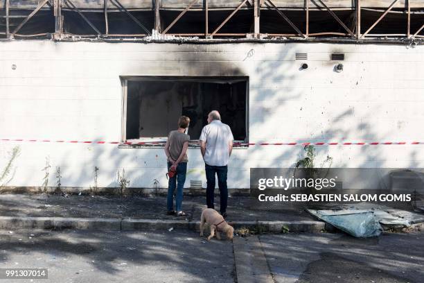 Residents stand in front of a burned medical center on July 4, 2018 in the Breil neighborhood of Nantes, following clashes between groups of young...