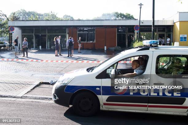 Police car drives past a burned medical center on July 4, 2018 in the Breil neighborhood of Nantes, following clashes between groups of young people...