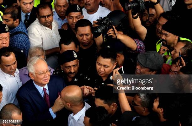 Najib Razak, Malaysia's former prime minister, bottom left, shakes hands with supporters as he leaves the Kuala Lumpur Courts Complex in Kuala...