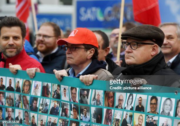 Members of the IG Metall union stand outside the headquarters of the Siemens AG before its annual press conference and hold up a banner reading 'Was...