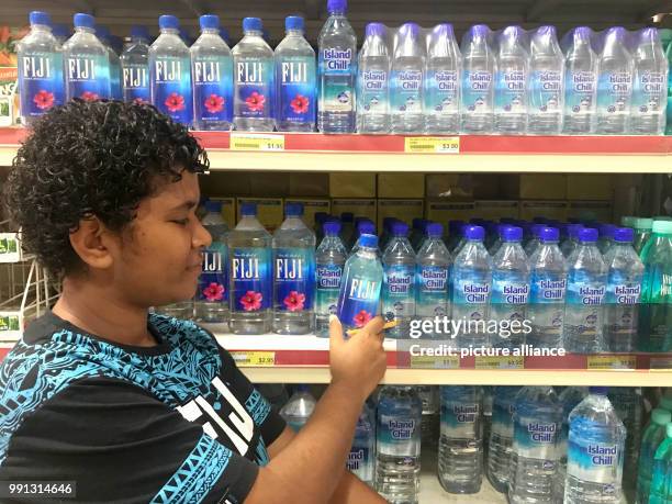 Woman examines a bottle of Fiji water in a supermarket in Nadi on the Fiji Islands, 20 October 2017. One liter of Fiji water sells on the Fiji...