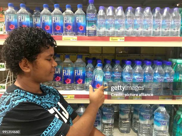 Woman examines a bottle of Fiji water in a supermarket in Nadi on the Fiji Islands, 20 October 2017. One liter of Fiji water sells on the Fiji...