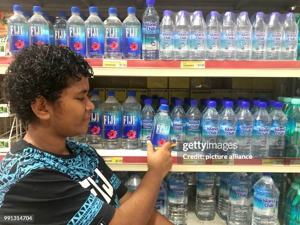 Woman examines a bottle of Fiji water in a supermarket in Nadi on the Fiji Islands, 20 October 2017. One liter of Fiji water sells on the Fiji...