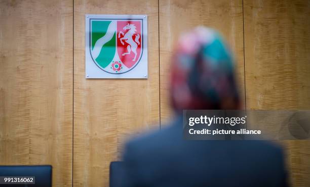 Representative of the council of Muslims sits in front of the federal coat of arms in the higher administrative court in Muenster, Germany, 9...