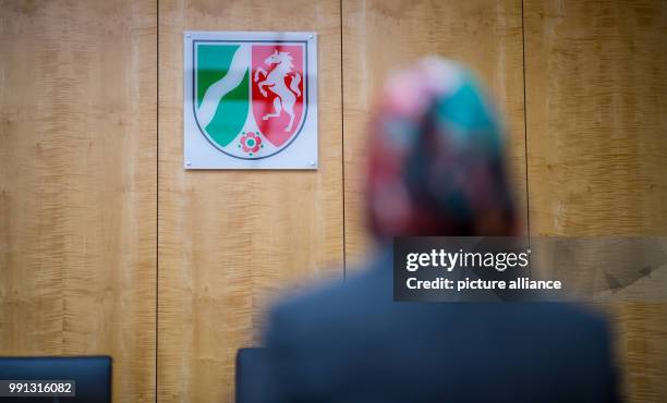 Representative of the council of Muslims sits in front of the federal coat of arms in the higher administrative court in Muenster, Germany, 9...