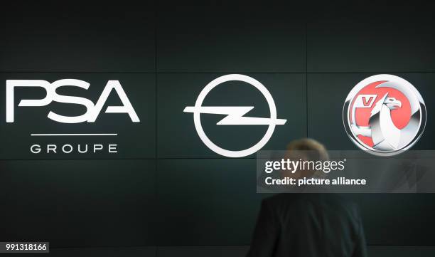 Man walks on the brink of a press conference by the company logos of Opel and PSA at the Opel Design Center in Ruesselsheim, Germany, 9 November...