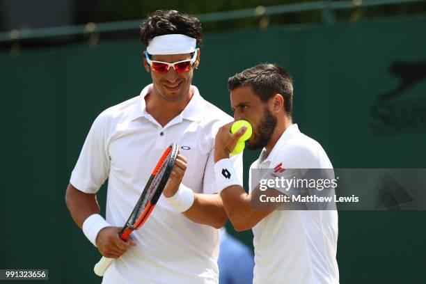 Ilija Bozoljac of Serbia and Damir Dzumhur of Bosnia and Herzegovina discuss tactics during their Men's Doubles first round match against Ken Skupski...