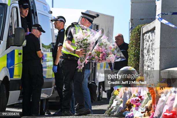 Policeman lay flowers for a member of the public at a house on Ardbeg Road on the Isle of Bute following the conformation that six year old...