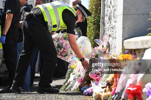 Policeman lay flowers for a member of the public at a house on Ardbeg Road on the Isle of Bute following the conformation that six year old...