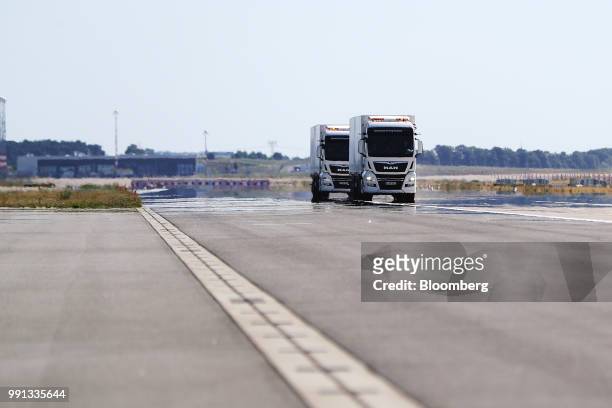 Pair of MAN SE TGX freight trucks pull trailers in convoy during a wireless communication technology "platooning" test drive on a runway at Berlin...