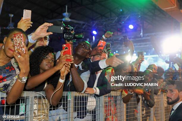 People take pictures of French President Emmanuel Macron as he arrives to take part of a live show at the Afrika Shrine in Lagos on July 3, 2018. -...