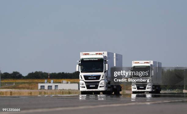 Pair of MAN SE TGX freight trucks pull trailers in convoy during a wireless communication technology "platooning" test drive on a runway at Berlin...