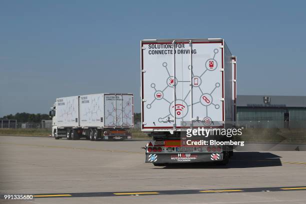 Pair of MAN SE TGX freight trucks pull trailers in convoy during a wireless communication technology "platooning" test drive on a runway at Berlin...