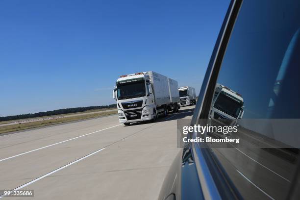 Pair of MAN SE TGX freight trucks pull trailers in convoy during a wireless communication technology "platooning" test drive on a runway at Berlin...