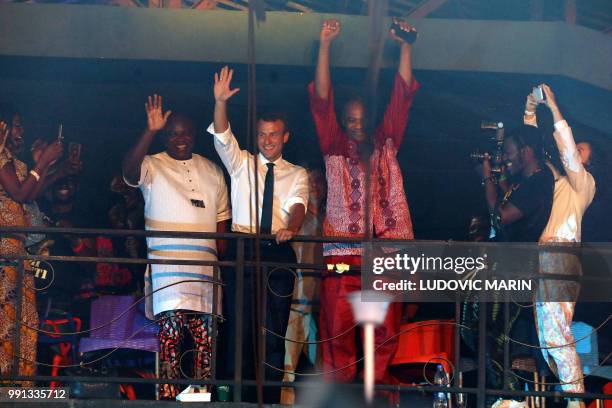 French President Emmanuel Macron and artist Femi Kuti wave to the crowd during a visit to the Afrika Shrine during a live show in Lagos on July 3,...