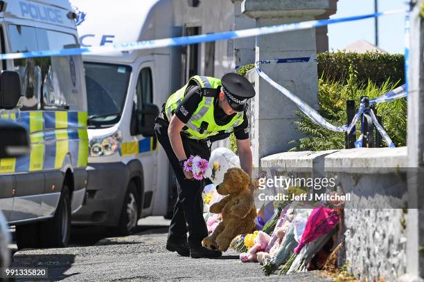 Policeman lay flowers for a member of the public at a house on Ardbeg Road on the Isle of Bute following the conformation that six year old...