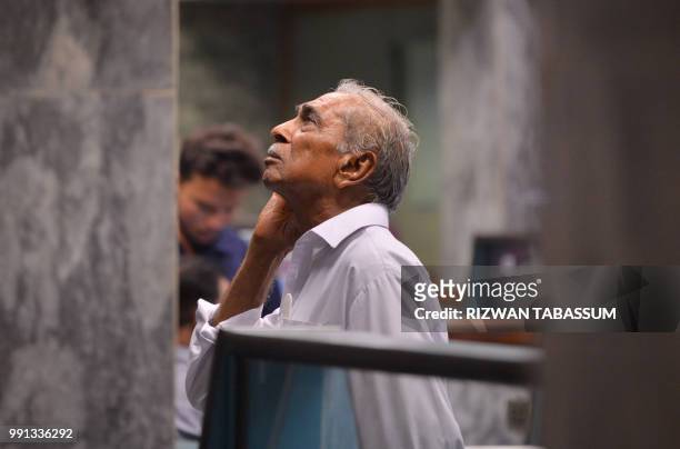 Pakistani stockbroker looks at the latest share prices on a digital board during a trading session at the Pakistan Stock Exchange in Karachi on July...