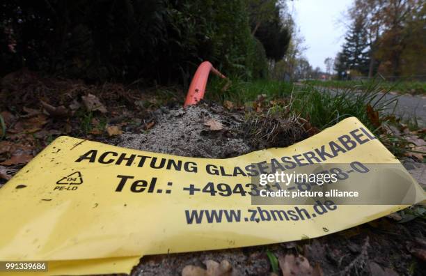 Fibre-optic connection sticks out of a contruction site with a plactic sign saying: "Warning fibre-optic connection" in Westerroenfeld, Germany, 9...