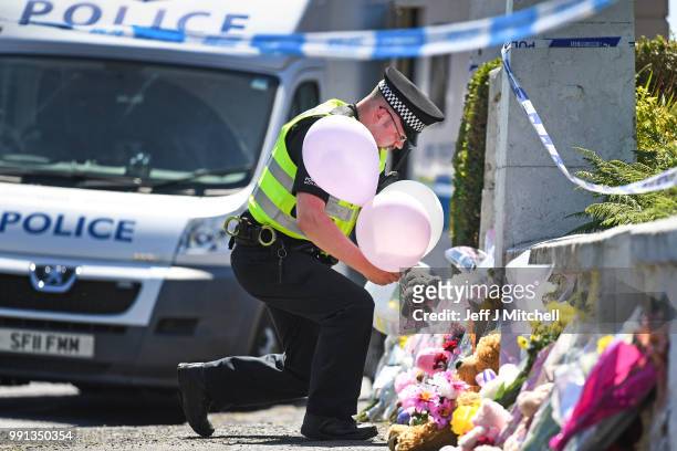 Policeman leaves balloons for a member of the public at a house on Ardbeg Road on the Isle of Bute following the conformation that six year old...