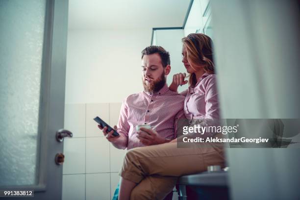 young couple drinking coffee and watching videos on smartphone - human body part videos stock pictures, royalty-free photos & images