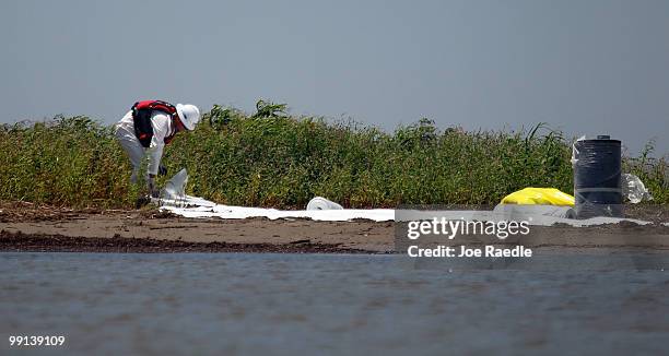 Worker cleans a beach after tar balls washed up as efforts continue to contain BP's massive oil spill on May 12, 2010 in South Pass, Louisiana. The...