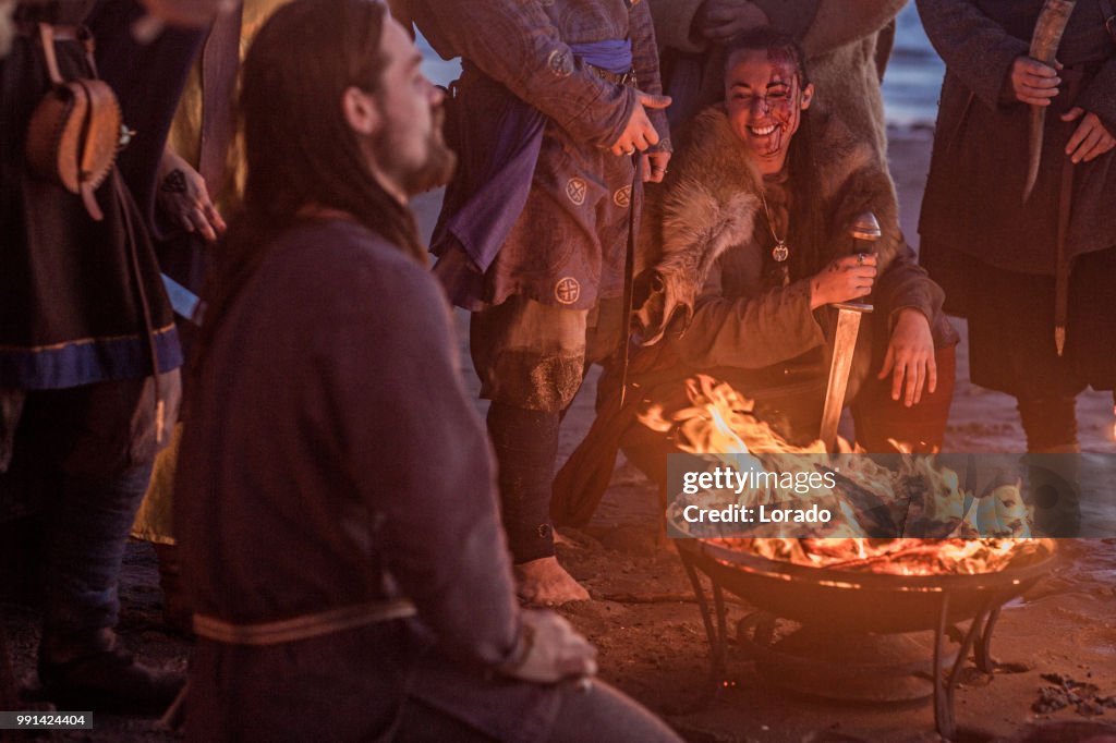 Un gruppo di guerrieri vichinghi seduti attorno a un falò di notte in mare