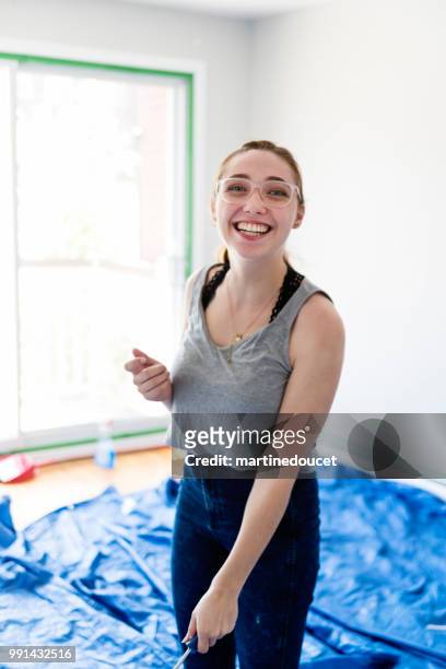 jonge vrouw schilderij woonkamer in eerste appartement. - martine doucet or martinedoucet stockfoto's en -beelden