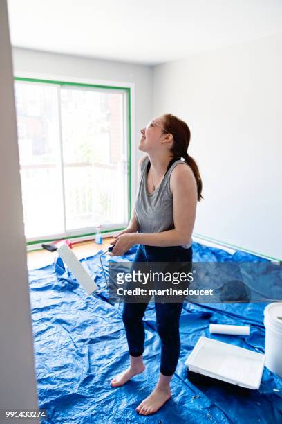 jonge vrouw schilderij woonkamer in eerste appartement. - martine doucet or martinedoucet stockfoto's en -beelden