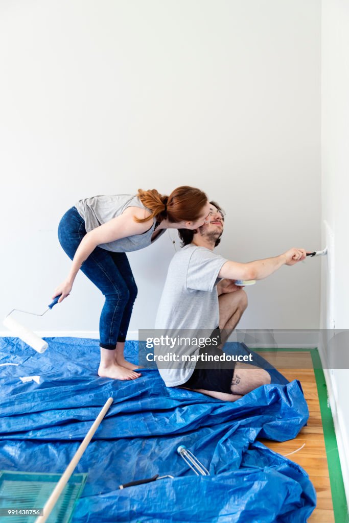 Young couple painting living room in first appartement.