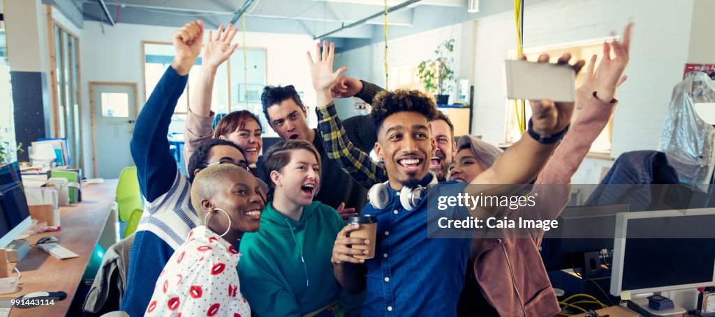 Enthusiastic creative business team taking selfie in office