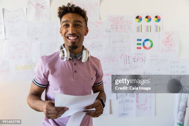 portrait smiling, confident creative businessman hanging paperwork on office wall - crowdsourcing imagens e fotografias de stock