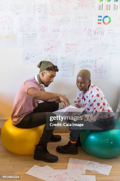 creative business people on fitness balls meeting, brainstorming and discussing paperwork in office - crowdsourcing imagens e fotografias de stock
