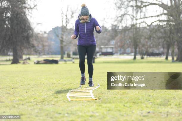 woman doing speed ladder drill in sunny park - agility ladder ストックフォトと画像