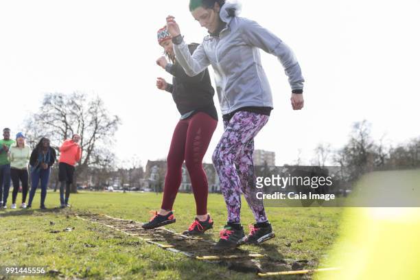 women exercising, doing ladder drill in sunny park - agility ladder stock pictures, royalty-free photos & images